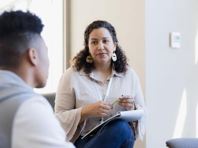 A woman holds a pen and listens to a boy